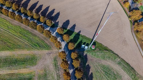 An antenna mast can be seen in a field in the middle of an autumn environment. The trees along the