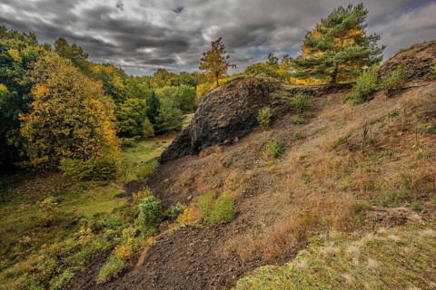 The scene shows a varied autumn landscape with colorful trees. The sky is cloudy and makes the