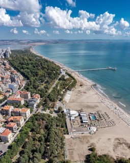 City beach with a long pier extending into the ocean. Aerial view to bech and sea garden of Burgas,