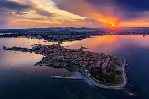 Aerial view of a peninsula at sunset with an orange sky and calm sea. Aerial view to old town of