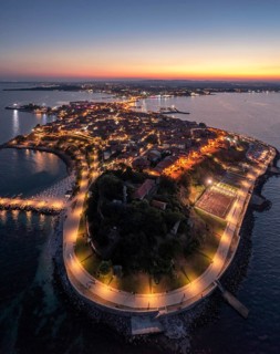 Historic peninsula illuminated at twilight, surrounded by calm sea waters. Aerial view to old town