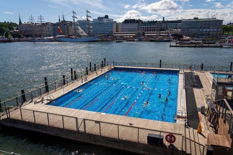 HELSINKI, FINLAND - JULY 6 2024: People enjoying public sea swimming pool and traditional sauna on
