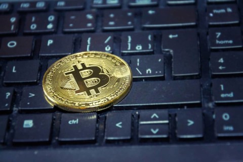 Golden bitcoin coin lying on green computer keyboard, cryptocurrency investing concept Prague Czech