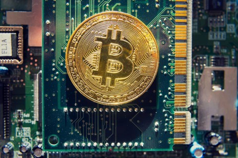Golden bitcoin coin lying on computer motherboard, cryptocurrency mining concept Prague Czech