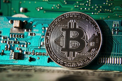 Silver bitcoin coin in front of computer motherboard, cryptocurrency mining and investing concept