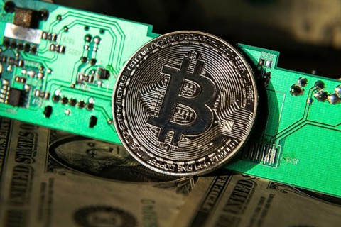 Silver bitcoin coin with dollars and computer motherboard, cryptocurrency mining concept Prague