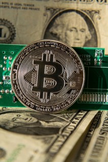 Silver bitcoin coin with dollars and computer motherboard, cryptocurrency mining and investing