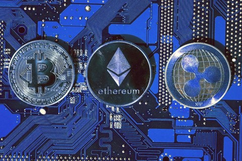Bitcoin, Ethereum, Ripple coins on computer motherboard, cryptocurrency investing concept Prague,
