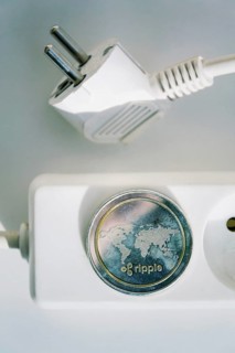 Ripple coin lying on power strip extension cord with empty socket, cryptocurrency investing, energy