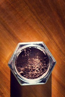 Cocoa powder in glass jar lying on wooden brown table, flat lay view, healthy diet Prague Czech