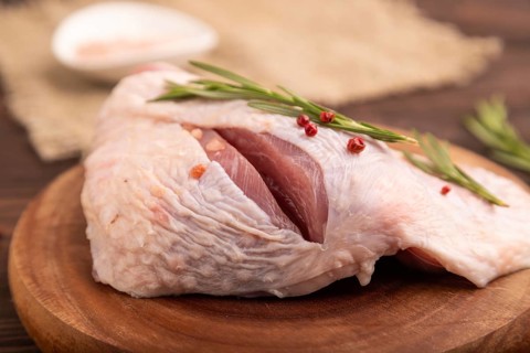 Raw Turkey Thigh with spices and rosemary on cutting board on brown wooden background and linen
