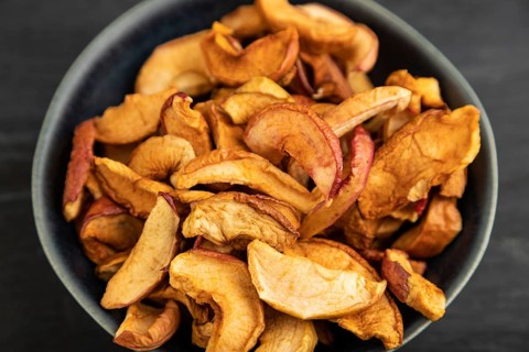 Dried Apples in ceramic bowl on black wooden background. Side view, close up. healthy food,