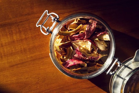 Dried apples and pears in open glass jar lying on wooden table, organic fruit food, healthy