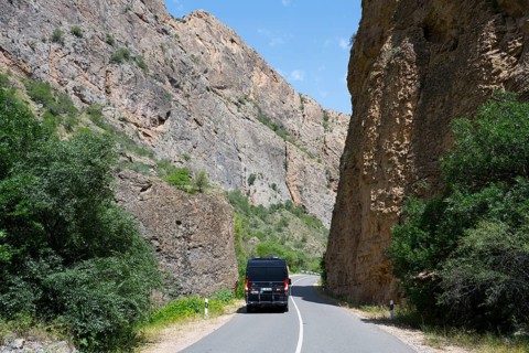Road through rocky landscape with a black van, camper drives through the Amaghu Gorge from Noravank
