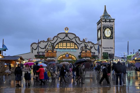 Oktoberfest visitors with umbrellas, rainy meadows, Augustiner festival tent, Munich, Bavaria,
