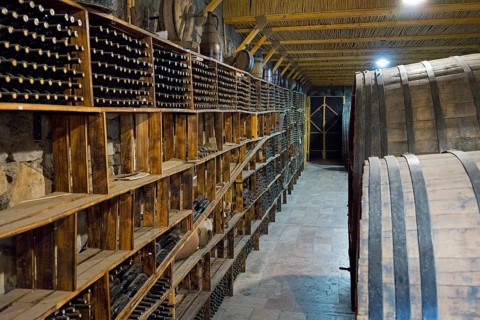 A wine cellar with wooden shelves and large barrels conveys a rustic atmosphere, Hin Areni Winery,