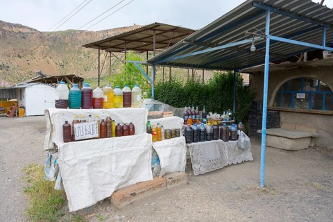 Market stand full of plastic bottles under a covered area selling wine and food in Areni village,