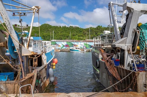 Two large, rusty fishing boats in the Port du Legue harbour at the mouth of the Legue. In the