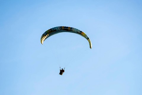 A single paraglider in front of a simple and minimalistic blue sky, Schwangau, Ostallgäu, Swabia,