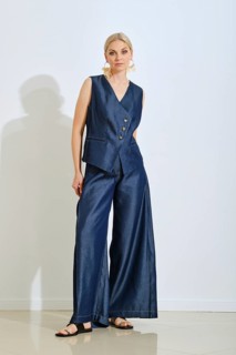 A woman models a fashionable navy vest and wide-leg pants in a contemporary studio. Natural light