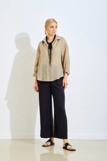A model stands confidently in a bright studio space wearing a stylish beige top and black wide-leg