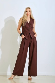A model stands confidently in a brown vest and matching pants. Her long hair flows down as she