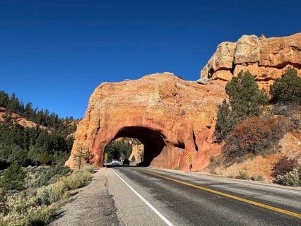 Red sandstone rock arch with a road leading through, in a vast desert landscape, Bryce Canyon