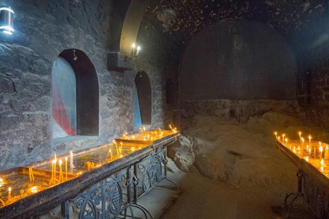 The room with candlelight creates a quiet, subdued atmosphere with stone walls, Khor Virap