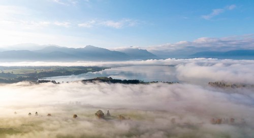 Morning fog covers a vast landscape with Lake Forggensee, near Roßhaupten, Ostallgäu, Allgäu,