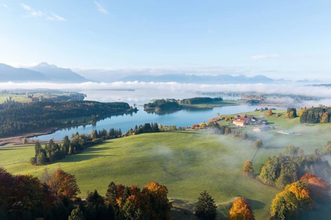 A picturesque view of Lake Forggensee surrounded by autumn landscape, near Roßhaupten, Ostallgäu,