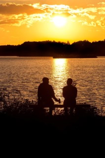 Two men sitting on a bench at sunset at Lake Gudelack, Lindow (Mark), Stechlin-Ruppiner Land nature