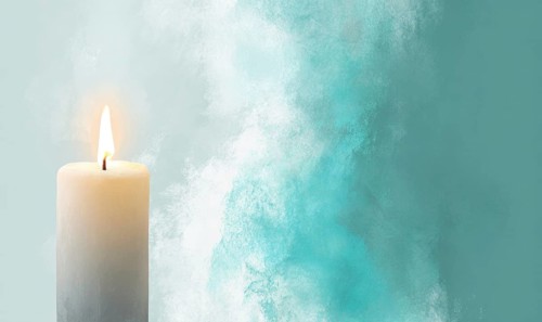 A candle is lit in front of a blue background. The candle is the main focus of the image, and it