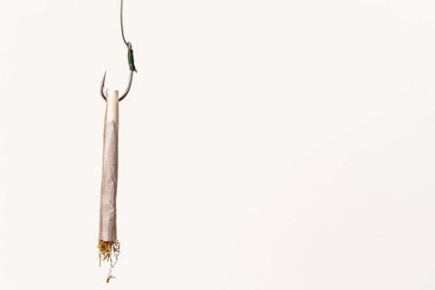 Rolled cigarette on a fishing hook, symbolizing the dangers of tobacco addiction and the lure of