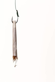Hand rolled cigarette acting as bait on a fishing hook, symbolizing addiction, danger, and the