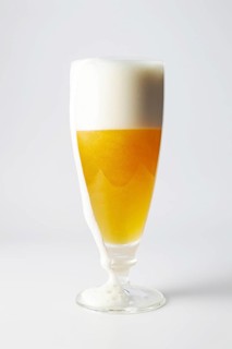 A glass of beer with foam running off, copy space