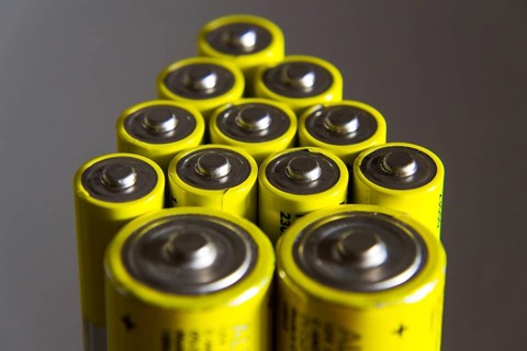 Stack of yellow AA batteries close up, electricity storage concept