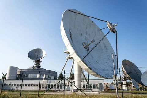 Barbed wire fence around satellite links center with telecommunication tower equipped with radar