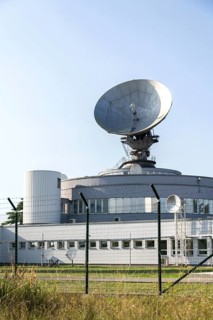 Barbed wire fence around satellite links center with telecommunication tower equipped with radar