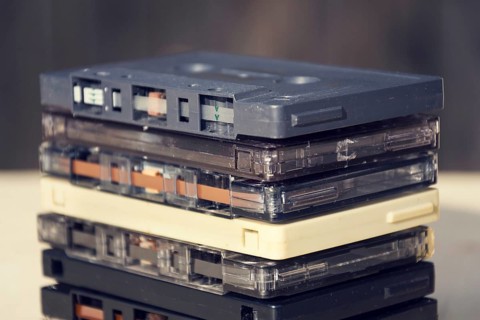 Filtered retro compact cassette audio magnetic tapes on wooden background