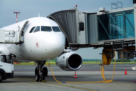 Charter airline airplane preparing for flight on airport runway with connected jet boarding bridge