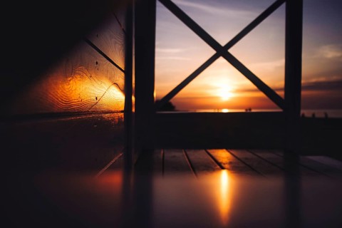 A warm sunset over the sea viewed through a wooden structure with visible reflections. Sea, Baltic,