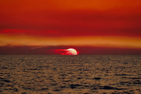 Sunset over the sea with a vivid red sky and gentle waves. Baltic, sea, Poland, Kolobrzeg