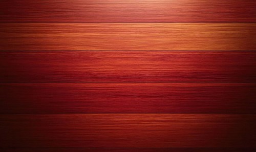 A close up of a wooden surface with a reddish brown color. The surface is made up of wooden planks