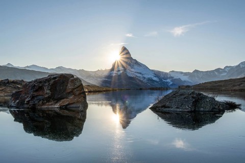 Matterhorn Mountain and Reflection in Lake Stellisee at Sunset. Sun is Setting behind the Mountain.