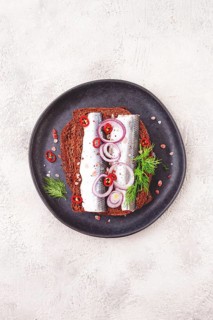 Sandwiches, herring fish, on dark rye bread, sprinkled with onion, chili pepper and herbs, on a