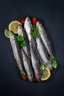 Fresh Herring fish, ready to cook, with herbs and spices, on black slate, in the kitchen