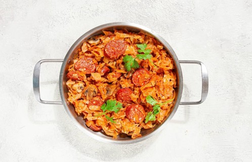 Polish dish bigos, in a stainless steel pan, stewed meat with cabbage, chorizo sausages, mushrooms,