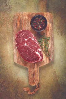 Steak made from fresh beef, with herbs and various spices, on a wooden chopping board, ready to