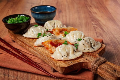 Gyoza Japanese dumplings, fried, with sauce, with green onion and sesame seeds, no people,