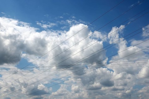 Intersecting high-voltage lines cut through a blue sky with white clouds, Upper Bavaria, Bavaria,